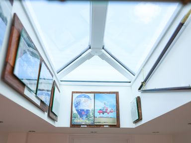 A skylight ceiling with framed pictures of a hot air balloon and a gyrocopter on the walls at Howard Cottage in North Littleton near Offenham