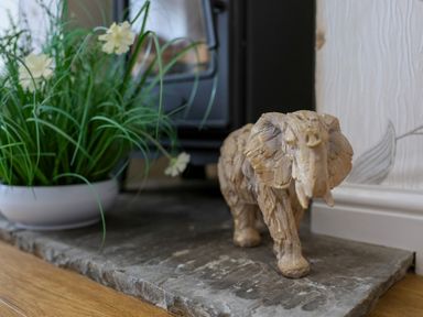 A wooden elephant figurine next to a plant with white flowers on a stone surface at Howard Cottage in North Littleton near Offenham