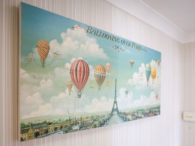 A painting of hot air balloons flying over Paris with the Eiffel Tower in the background at Howard Cottage North Littleton near Offenham