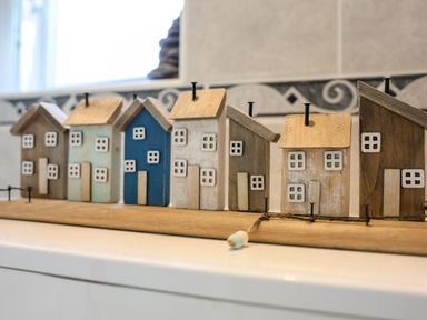 A row of small decorative wooden houses on a shelf at Howard Cottage in North Littleton near Offenham