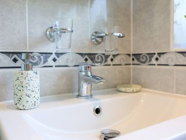 A bathroom sink with a soap dispenser a faucet two glass holders and a soap dish at Howard Cottage in North Littleton near Offenham