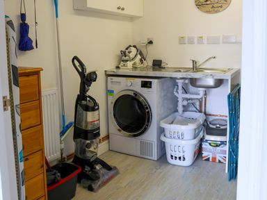 A laundry room with washing machine sink vacuum cleaner and laundry baskets at Howard Cottage North Littleton near Offenham