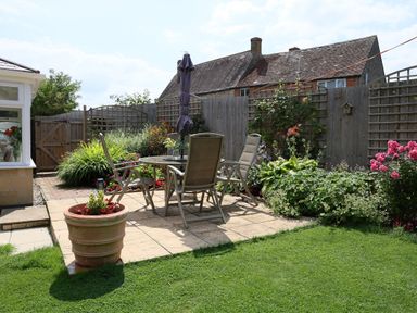 A garden patio with a table and four chairs surrounded by plants and flowers at Howard Cottage North Littleton near Offenham