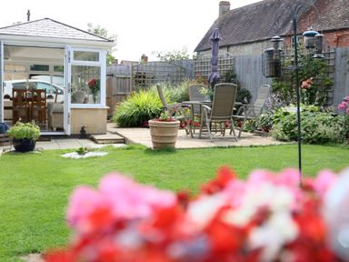 A garden with patio furniture and plants near a conservatory at Howard Cottage in North Littleton near Offenham