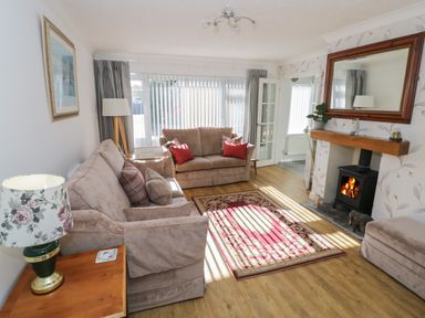 A living room with sofas a fireplace a rug and a large mirror at Howard Cottage in North Littleton near Offenham