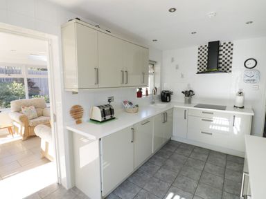 A kitchen with white cabinets a toaster a sink a stove and a patterned extractor fan at Howard Cottage in North Littleton near Offenham