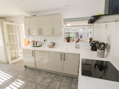 A kitchen with white cabinets a countertop with a toaster an air fryer and cooking utensils at Howard Cottage North Littleton near Offenham