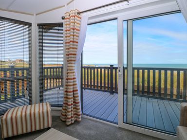 A room with sliding glass doors leading to a deck with a sea view at Seaview Lodge in Bacton