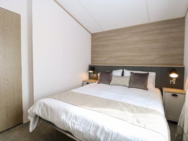A bedroom with a double bed two bedside tables and wall lamps at Seaview Lodge in Bacton