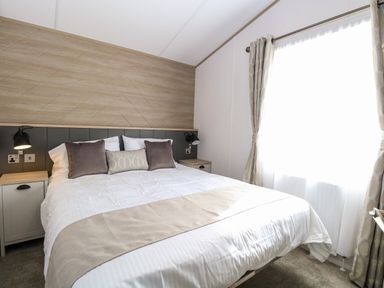 A bedroom with a double bed two bedside tables and curtains at Seaview Lodge in Bacton