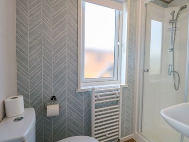 A bathroom with a toilet a shower cubicle a washbasin and a window at Seaview Lodge in Bacton