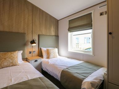 A bedroom with two single beds a bedside table and window at Seaview Lodge in Bacton