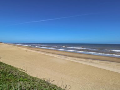 A sandy beach with gentle waves and a clear blue sky at Seaview Lodge in Bacton