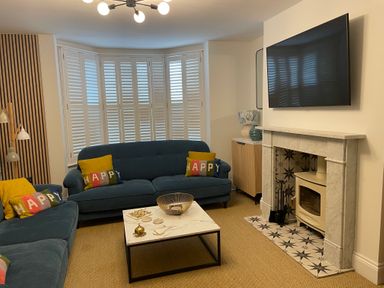A living room with blue sofas and a marble coffee table in front of a fireplace with a mounted TV at Happy Place in Sheringham