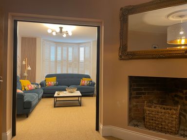 A living room with blue sofas and colorful cushions and a coffee table with a bowl at Happy Place in Sheringham