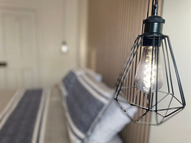 A bedroom with a bed and hanging industrial style light fixtures at Happy Place in Sheringham