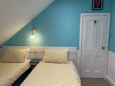 A bedroom with two single beds with yellow chevron patterned bedding and a white door at Happy Place in Sheringham