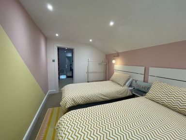 A bedroom with two single beds with chevron patterned bedding and a clothing rack at Happy Place in Sheringham
