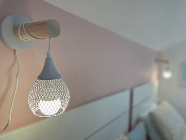 A close up of a wall-mounted light fixture above a bed at Happy Place in Sheringham