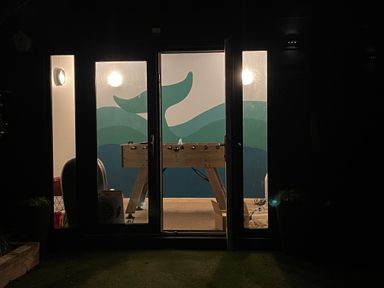 A game room with a foosball table and wave mural on the wall at Happy Place in Sheringham