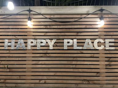 Metal letters spelling HAPPY PLACE on a wooden slat wall with string lights above at Happy Place in Sheringham