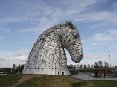 Large metal horse head sculpture outdoors with people walking nearby at Oak in Denny