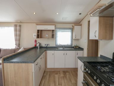A kitchen with cabinets a gas stove a sink a kettle and a fire extinguisher at Hazel in Denny