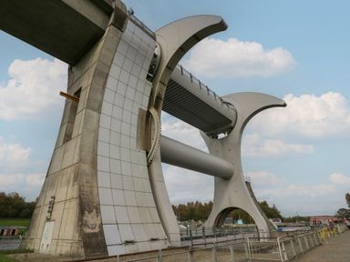 A large rotating boat lift structure with concrete supports and metal components under a partly cloudy sky