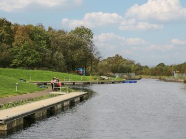 A river with docks and people fishing on the grassy bank at Birch in Denny