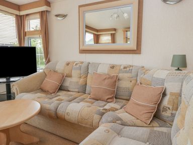 A living room with a sofa and television at Birch in Denny
