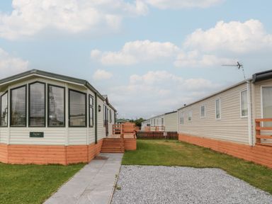 A caravan with a pathway and grass area at Birch in Denny