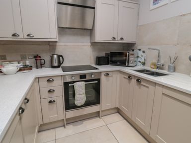 A kitchen with beige cabinets a built in oven an electric kettle a microwave and a dual sink at The Coquet Nest in Rothbury