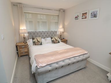 A bedroom with a bed with tufted headboard and two bedside tables with lamps at The Coquet Nest in Rothbury