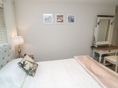 A bedroom with a bed a bedside lamp a pillow with a giraffe print and a dressing table with a mirror at The Coquet Nest in Rothbury