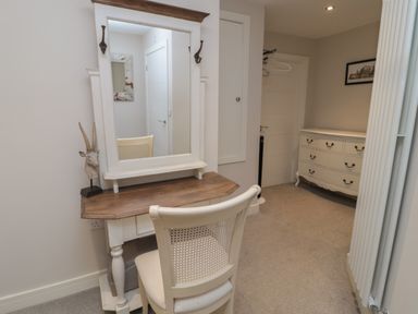 A dressing table with a mirror and chair in a room with a chest of drawers at The Coquet Nest in Rothbury