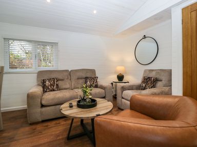A sitting area with a sofa armchair wooden coffee table lamp and round mirror at Esk Pike 9 Skiptory Howe White Cross Bay near Windermere