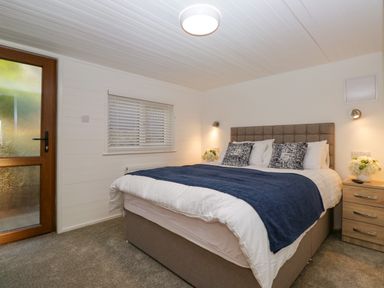 A bedroom with a double bed bedside tables with flowers and a window at Esk Pike 9 Skiptory Howe White Cross Bay near Windermere