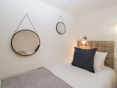 A bedroom with a bed a tufted headboard two round hanging mirrors and a reading light at Esk Pike 9 Skiptory Howe White Cross Bay near Windermere