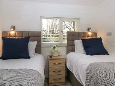A bedroom with two single beds a bedside table with flowers and a window with blinds at Esk Pike 9 Skiptory Howe White Cross Bay near Windermere