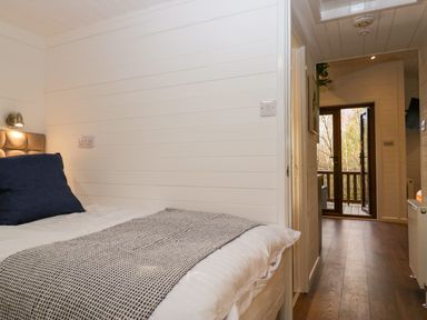 A bedroom with a bed and hallway leading to a door opening to a balcony at Esk Pike 9 Skiptory Howe White Cross Bay near Windermere