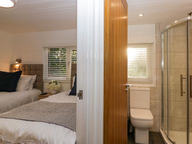 A bedroom with two beds and a bedside table next to a bathroom with a toilet and shower at Esk Pike 9 Skiptory Howe White Cross Bay near Windermere
