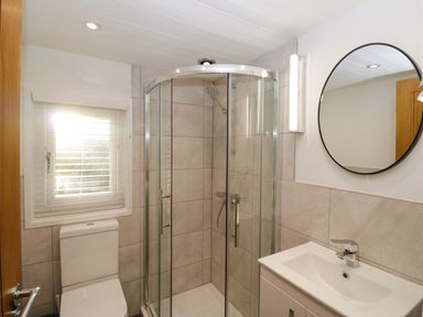 A bathroom with a shower enclosure toilet sink and round mirror at Esk Pike 9 Skiptory Howe White Cross Bay near Windermere