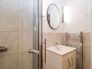 A bathroom with a sink vanity unit a round mirror and a chrome towel radiator at Esk Pike 9 Skiptory Howe White Cross Bay near Windermere