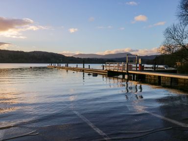 A wooden pier extending into a lake with hills in the background at Esk Pike 9 Skiptory Howe White Cross Bay near Windermere