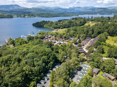 An aerial view of a lakeside village with small houses surrounded by trees and boats on the water at Esk Pike 9 Skiptory Howe White Cross Bay near Windermere
