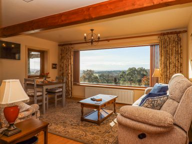 A living room with a sofa a coffee table a dining table and large window with a view at Sherway Dairy in Clyst Hydon near Bradninch