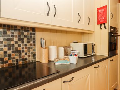 A kitchen countertop with a knife block paper towel holder toaster microwave and oven at Sherway Dairy in Clyst Hydon near Bradninch