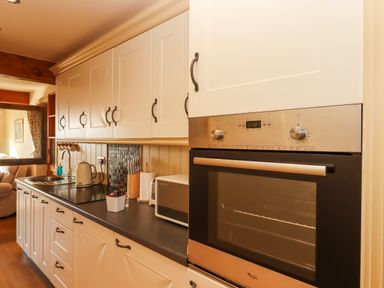 A kitchen with white cabinets black countertop a built in oven microwave kettle and a knife block at Sherway Dairy in Clyst Hydon near Bradninch