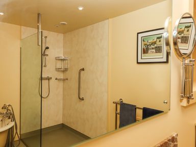 A bathroom with a walk-in shower a bathtub a towel rack with towels and a wall mirror at Sherway Dairy in Clyst Hydon near Bradninch