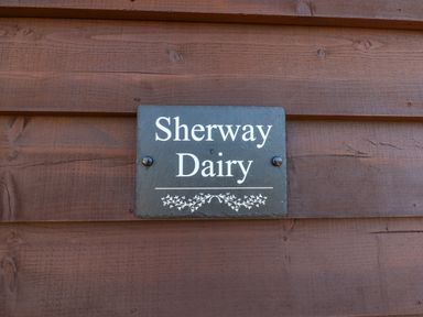 A sign with Sherway Dairy text mounted on wooden paneling at Sherway Dairy in Clyst Hydon near Bradninch